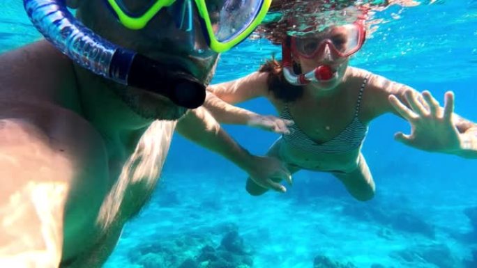 夏天在海里浮潜。夫妇向可穿戴相机挥手。水下射击