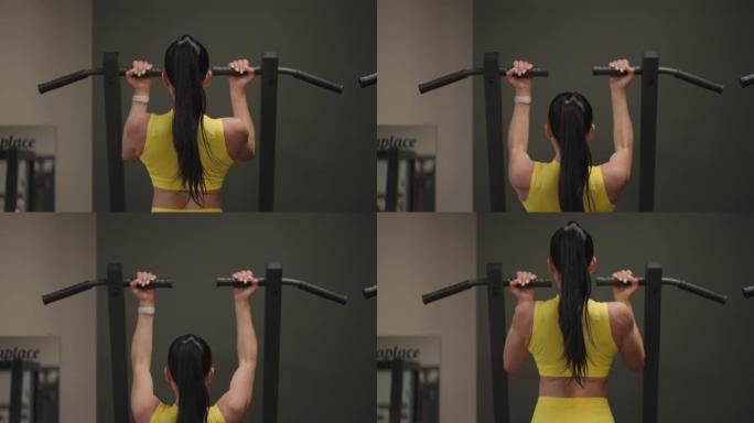 西班牙裔妇女在Gravitron上进行引体向上，以增强健身房中的肩部肌肉。一个女人正确地做练习，挺直