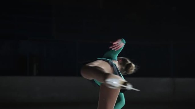 慢动作中等，一位才华横溢的女运动员准备在前一天晚上参加比赛。一个女孩站在一条腿上执行花样滑冰旋转的基