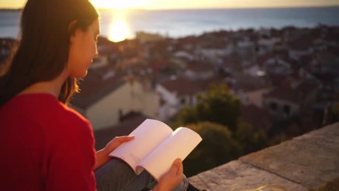 日落时在壁架上看书的年轻女子