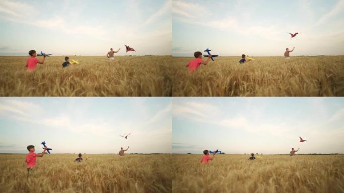 小男孩在夏天的黄金麦田里一起奔跑，放风筝和玩具飞机