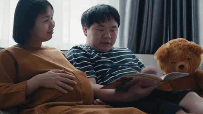 亚洲男人和她怀孕的妻子看书。