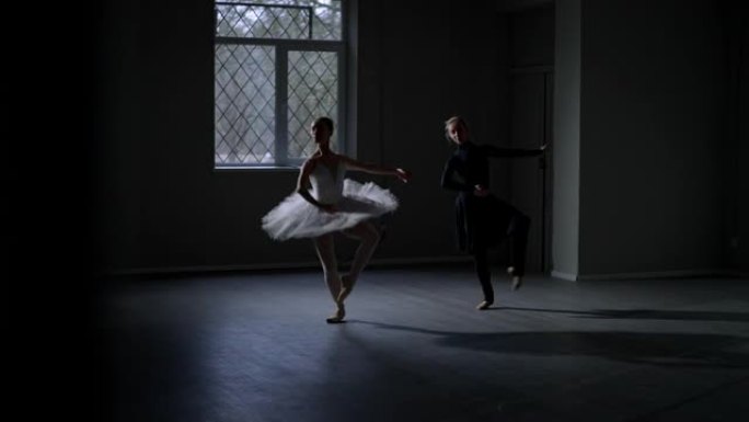 两个苗条的年轻女子在黑暗中跳芭蕾舞。高加索才华横溢的苗条芭蕾舞演员在passe步行同时在室内舞蹈工作
