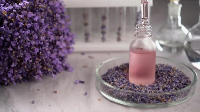 带淡紫色精油的滴管，特写镜头，带紫色薰衣草花和精油瓶的水疗背景。