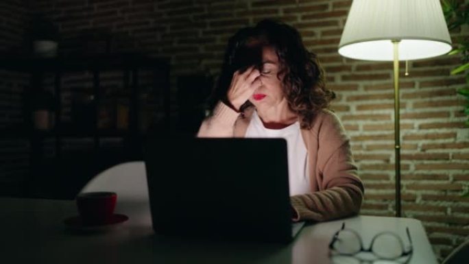 中年妇女在家中使用笔记本电脑感到疲倦