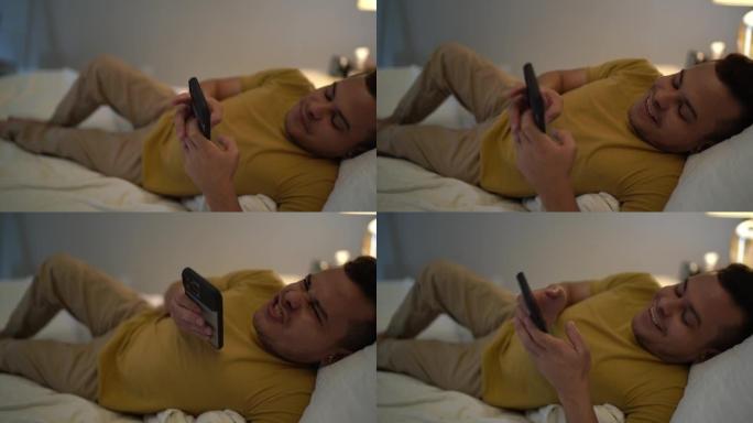 矮人的年轻人躺在家里的床上在智能手机上发送音频消息