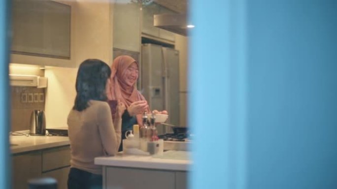 亚洲马来妇女白癜风皮肤状况在厨房准备早餐并与她的女性朋友交谈