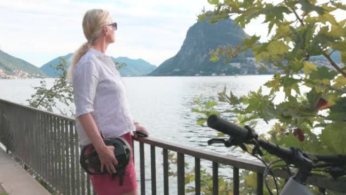 女人使用智能手机在俯瞰湖泊的栏杆上放松