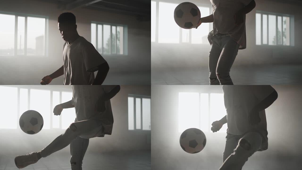 一个特写的黑人在车库的阳光下玩足球。城市环境中日落时的足球自由泳。灰尘和日落
