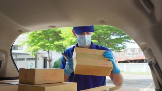 送货员在送货车后面检查并携带纸质包装箱。