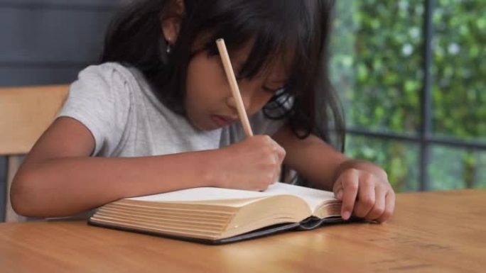 亚洲小学生在日记簿上写信。孩子学习和工作，看书，女孩在家工作。可爱的孩子做和学习作业。小孩子开心微笑