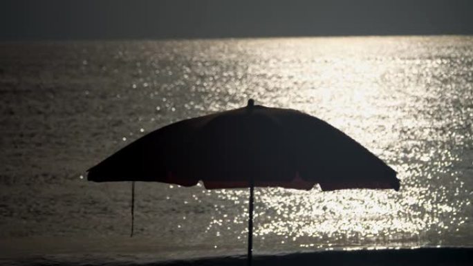 太阳伞，沙滩，在大海中日落的倒影背景下