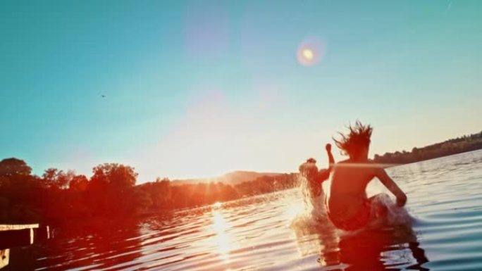 SLO MO TS年轻男女在日落时跳入湖中