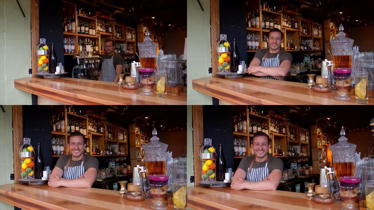 快乐的拉丁美洲调酒师在酒吧工作，靠在柜台上面对相机微笑