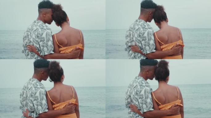 热爱非洲种族的夫妇在海滩上拥抱。远望大海