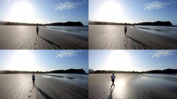 年轻女子在日出时沿着空旷的海滩奔跑