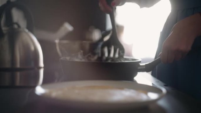 女人正在烹饪自制食物，周日早上煎煎饼，炉子和煎锅的特写镜头
