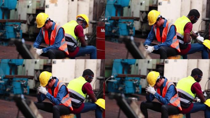 又累又热。亚洲男性和非裔美国工程师工人戴着安全安全帽头盔。金属车床工业制造厂