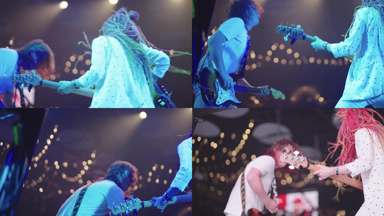 成年男性贝斯手和年轻女性时尚吉他手，留着辫子，在舞台上抽水