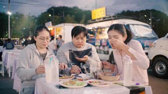 亚洲朋友晚上在the Foot Truck City聚会共进晚餐，分享食物并享受乐趣。