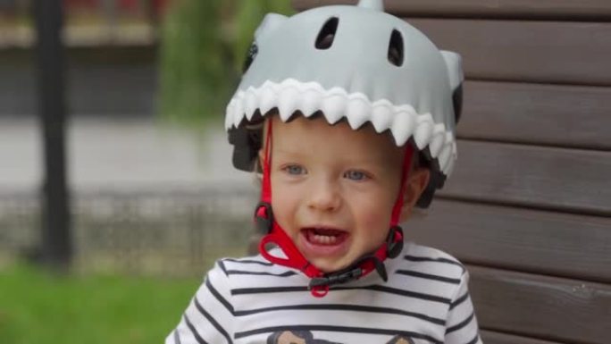 穿着有趣的自行车头盔的孩子在户外为幼儿学习骑三轮车，蹒跚学步的男孩在夏季公园玩得开心。儿童户外游乐场