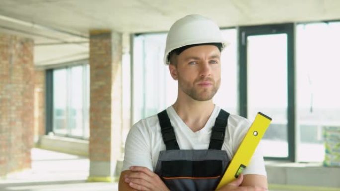 在建筑工地，一位工程师戴着黄色的头盔，手持平衡尺。气泡水平尺近距离观察，测量和水准概念
