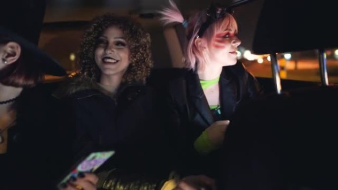三名年轻女子乘坐出租车参加万圣节派对并使用手机