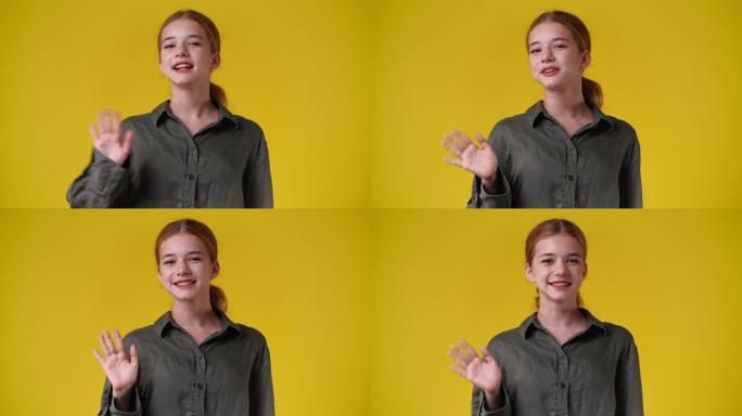 一个女孩在黄色背景上挥手打招呼的4k慢动作视频。