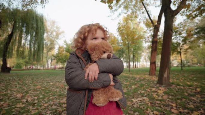 害怕的孩子带着熊玩具独自在公园散步，迷路，危险的地方