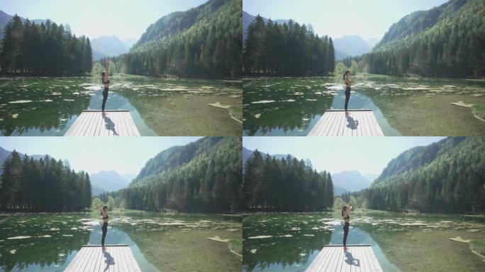 年轻女子在山和林景湖的码头尽头做瑜伽