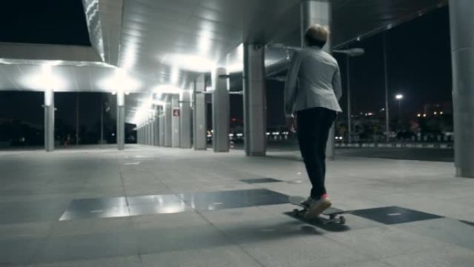 亚洲男子晚上在大城市骑着滑板上下班。