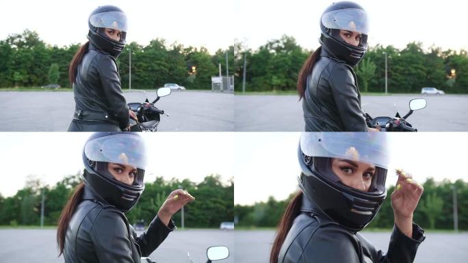 迷人的时尚苗条的年轻女子在保护头盔上摆姿势在相机上豪华摩托车开始骑在操场上