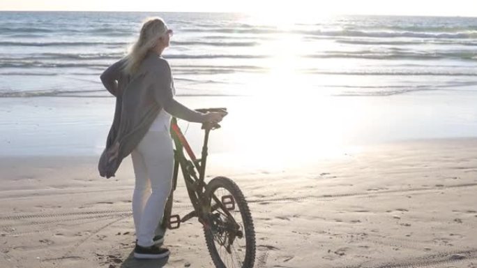 女人在空旷的海滩上推自行车