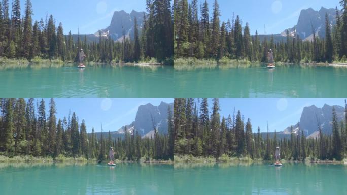 女人划桨在宁静的山湖上站起来划桨板