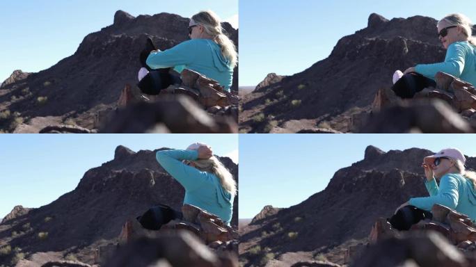 女徒步旅行者在沙漠上的岩石山脊上休息