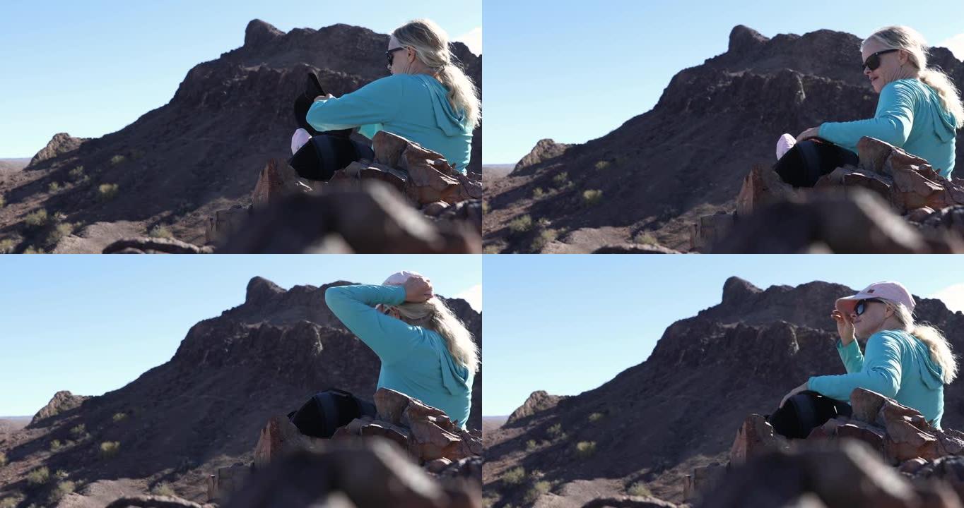 女徒步旅行者在沙漠上的岩石山脊上休息