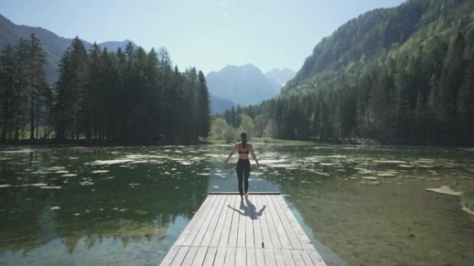 年轻女子在山和林景湖的码头尽头做瑜伽