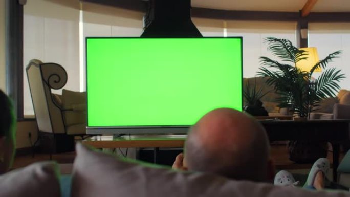 观看激烈体育比赛的朋友的后视图。带色度键的大电视屏幕。