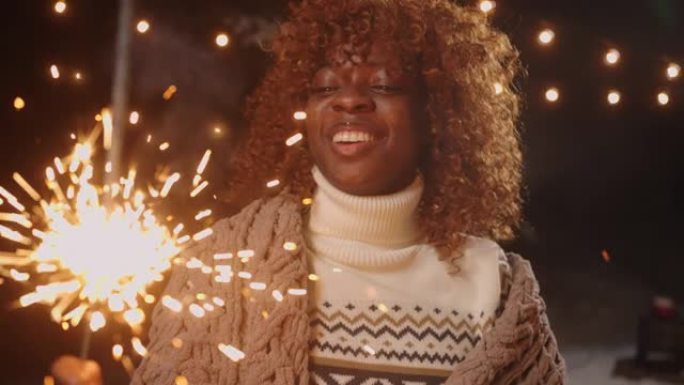 有趣的黑人女人在圣诞节或新年的快乐朋友派对上燃烧着烟火，肖像