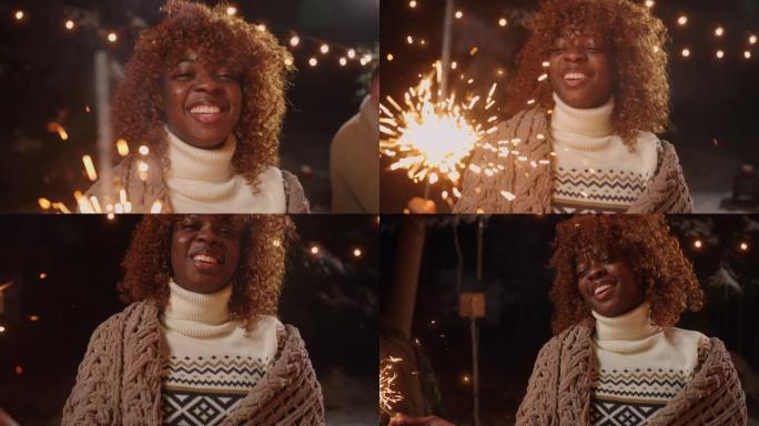 有趣的黑人女人在圣诞节或新年的快乐朋友派对上燃烧着烟火，肖像