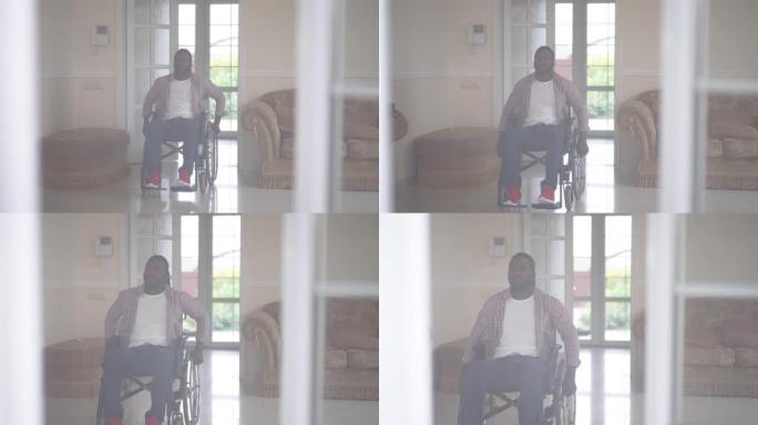 坐在轮椅上的玻璃胡须非洲裔美国人男子在室内慢动作滚动辅助设备。室内客厅的前视图残疾人。生活方式概念。