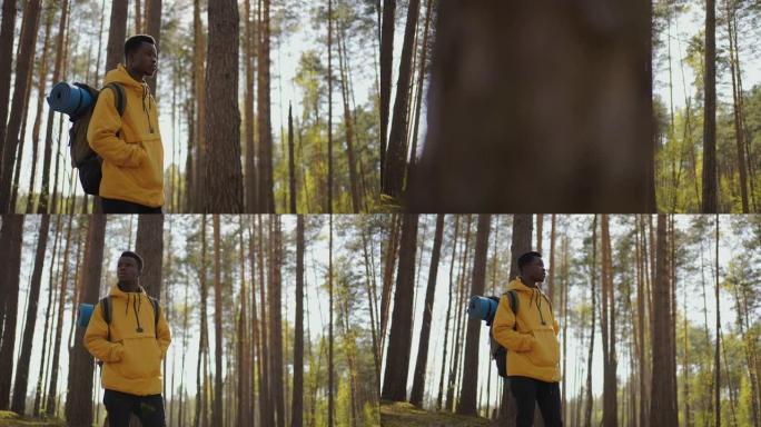 非洲黑人男子穿着黄色夹克在树林里爬坡，背包慢动作