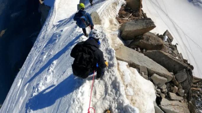 登山者团队在欧洲阿尔卑斯山的积雪覆盖的山峰上移动。使用绳索和攀爬设备。鸟瞰图