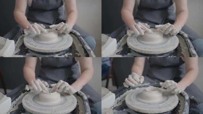 在陶工轮上工作的大师的手的特写镜头，以慢动作制造粘土和陶瓷罐和板