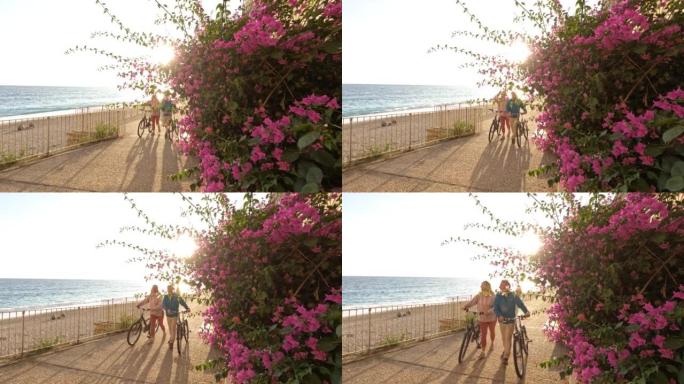 成熟的夫妇沿着海滩长廊推自行车