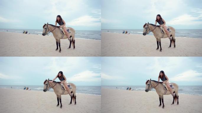 4K，一名年轻的亚洲女游客在海滩上骑马，在日落前的傍晚，游客可以骑马。海边的海滩区，波浪小，天气好。