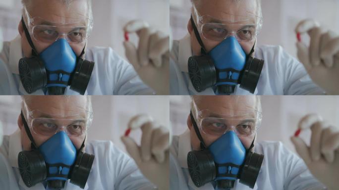 一家制药公司的科学家一名戴着蓝色呼吸器和安全眼镜的药品开发商拿着一种新药一颗红色药丸看着它