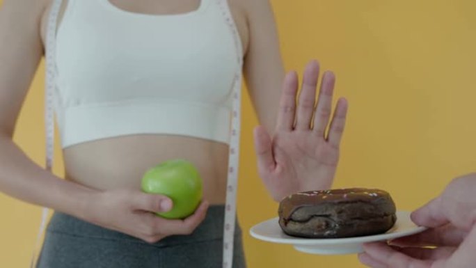 饮食和节食。美丽苗条的女性身体混淆甜甜圈。女人在运动服装达到减肥目标，为健康生活，疯狂瘦身，瘦腰，营