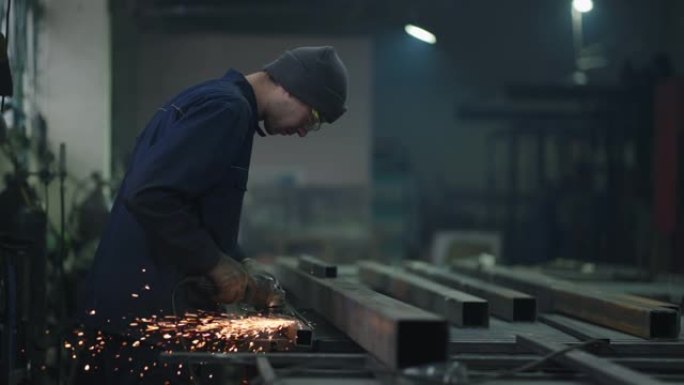重工业工人用角磨机切割钢材。重工业体力劳动者
