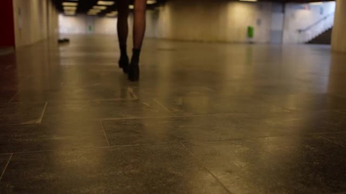 穿着高跟鞋和裙子的女孩走过地铁通行证